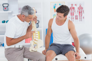 38333309 - doctor showing anatomical spine to his patient in medical office