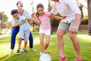 31065824 - family playing soccer in park together