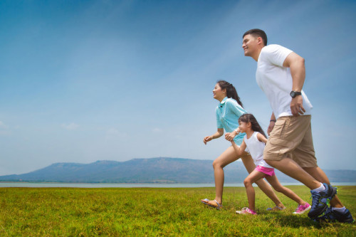 Asian family running on open grasslands.